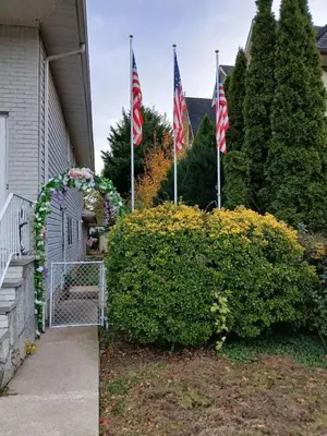 two american flags in front of a house at Family-Friendly Retreat With Trampoline & Grill in Locust Valley