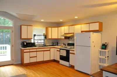 a kitchen with a white refrigerator and wooden floors at Family-Friendly Retreat With Trampoline & Grill in Locust Valley