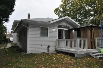 a small white house with a porch and a gazebo at Family-Friendly Retreat With Trampoline & Grill in Locust Valley