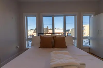 a bedroom with a large white bed with windows at Pristine Pad, Sleep 12, Free parking, 3BRs, 20 PERCENT OFF in East Newark