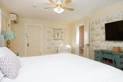 a bedroom with a white bed and a flat screen tv at The Berkshire Mountain Inn in Great Barrington