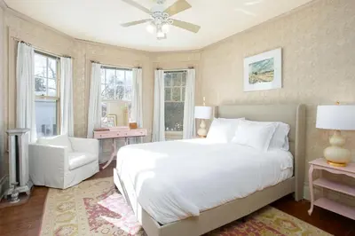 a bedroom with a white bed and a chair and windows at The Berkshire Mountain Inn in Great Barrington