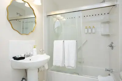 a white bathroom with a sink and a shower at The Berkshire Mountain Inn in Great Barrington