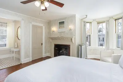 a bedroom with a white bed and a fireplace at The Berkshire Mountain Inn in Great Barrington