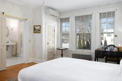 a bedroom with a large white bed and windows at The Berkshire Mountain Inn in Great Barrington