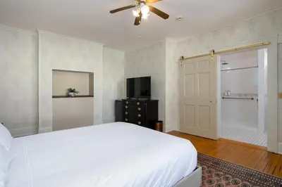 a bedroom with a white bed and a ceiling fan at The Berkshire Mountain Inn in Great Barrington