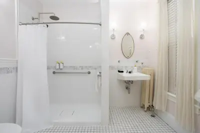 a white bathroom with a shower and a sink at The Berkshire Mountain Inn in Great Barrington