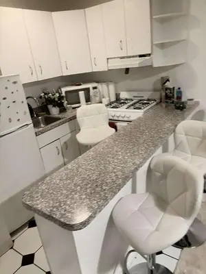 a kitchen with white cabinets and a granite counter top at Beautiful cozy place in HEART MANHATTAN in New York