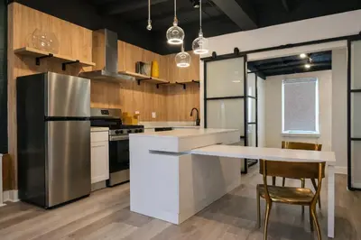 a kitchen with a stainless steel refrigerator and a table at Modern Loft Apartments, Stylish Design Near Midtown in New York