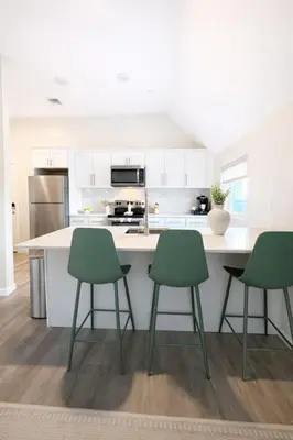 a kitchen with white cabinets and green chairs at Yale Getaway Parking Wooster Square King Bed in New Haven