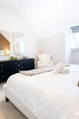 a bedroom with a large white bed and a chair at Yale Getaway Parking Wooster Square King Bed in New Haven