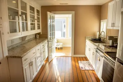 a kitchen with white cabinets and a wooden floor at Ann Inn - Downtown New Milford Apartment in New Milford