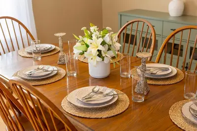 a wooden table with chairs and plates and a vase of flowers at Ann Inn - Downtown New Milford Apartment in New Milford
