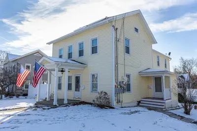 a white house with two american flags in the snow at Ann Inn - Downtown New Milford Apartment in New Milford
