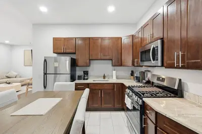 a kitchen with wooden cabinets and a stove top oven at Spacious 3BR 2BA Apt with Private Parking Walk to PATH in Jersey City