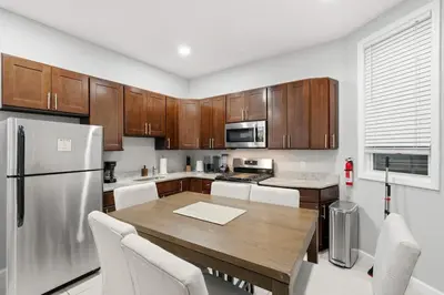 a kitchen with a table and a stainless steel refrigerator at Spacious 3BR 2BA Apt with Private Parking Walk to PATH in Jersey City