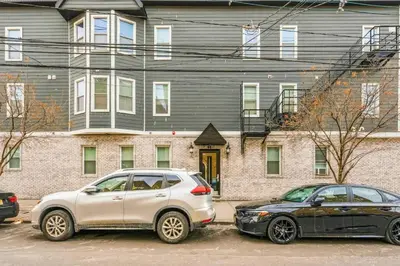 two cars parked in a parking lot in front of a building at Spacious 3BR 2BA Apt with Private Parking Walk to PATH in Jersey City