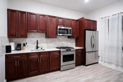 a kitchen with wooden cabinets and stainless steel appliances at Stylish & Comfortable City Stay in West New York