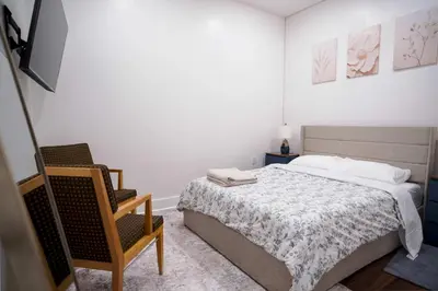 a white bedroom with a bed and a chair at Stylish & Comfortable City Stay in West New York