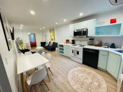 a kitchen with blue cabinets and a table and chairs at 2 Bedroom Garden Apartment Near Journal Square - Prime World Cup Lodging in Jersey City