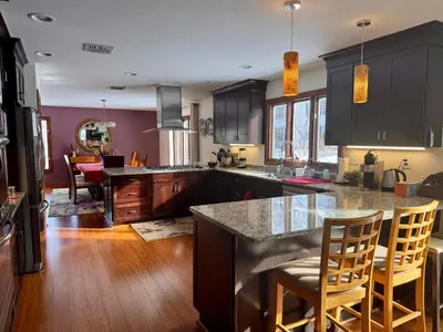 a kitchen with black cabinets and a kitchen island with chairs at Spacious 4BR Near Beaches WFH Office & Pool in Guilford