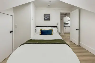 a white bedroom with a large bed with a blue pillow at Harbor Haven, Apt #4 - 2BR/1BA in Stamford