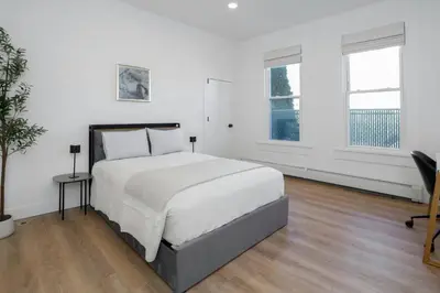 a white bedroom with a bed and a desk at Harbor Haven, Apt #5, 3BR/2BA in Stamford