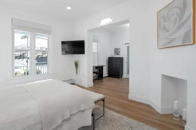 a white bedroom with a bed and a television at Harbor Haven, Apt #5, 3BR/2BA in Stamford
