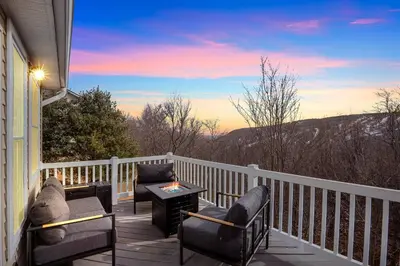 a porch with chairs and a table with a fire on it at Lux Camelback Summit: 5br, Hot Tub, Game Room in Tannersville