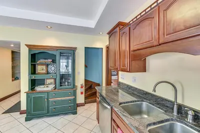 a kitchen with wooden cabinets and a sink at Dedicated Workspace! Home 2 Mi to Dtwn Schenectady in Schenectady