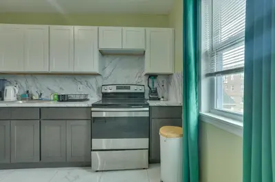 a kitchen with white cabinets and a stove and a window at Explore NYC, Parks and Beaches! Top-Floor Apt in Mount Vernon