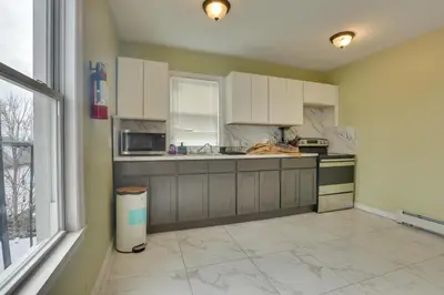 a kitchen with white cabinets and a large window at Easy NYC Access Updated Apt Near Parks and Bay! in Mount Vernon