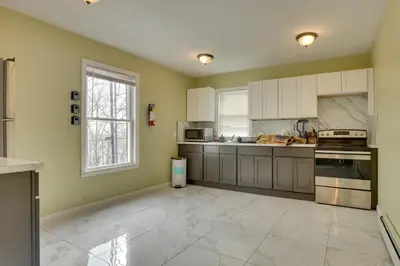 a large kitchen with white cabinets and a window at Easy NYC Access Updated Apt Near Parks and Bay! in Mount Vernon