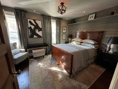 a bedroom with a large bed and a chair at Stylish Mission-Style Home on Park in Jersey City, NJ in Jersey City