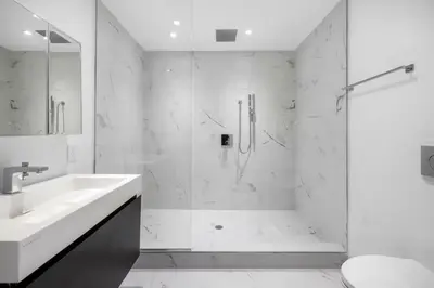a white bathroom with a shower and a sink at Fully renovated 3 BDR Apt East Village in New York