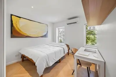 a bedroom with a bed and a table and a painting at Fully renovated 3 BDR Apt East Village in New York
