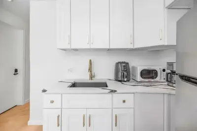 a white kitchen with white cabinets and a sink at Fully renovated 3 BDR Apt East Village in New York