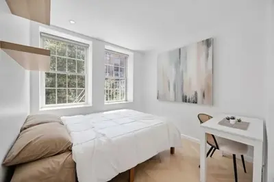 a bedroom with a bed and a desk and two windows at Bright Luxury 3-Bedroom Apartment in East Village in New York