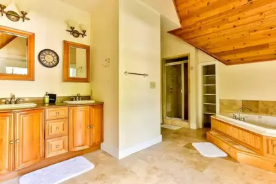 a bathroom with two sinks and a tub and a clock at Stunning 5BR at Hunter and Windham w Oversized Deck, 5 Acres, and Mountain View in Jewett