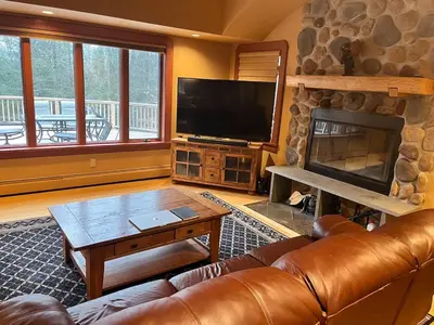 a living room with a leather couch and a fireplace at Stunning 5BR at Hunter and Windham w Oversized Deck, 5 Acres, and Mountain View in Jewett