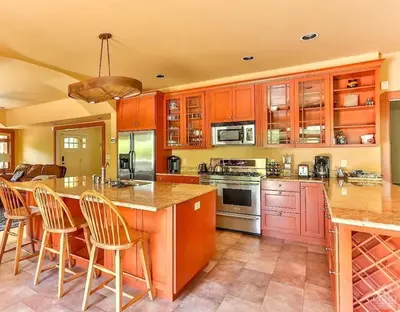a kitchen with wooden cabinets and a island with bar stools at Stunning 5BR at Hunter and Windham w Oversized Deck, 5 Acres, and Mountain View in Jewett