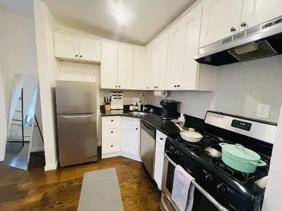 a kitchen with white cabinets and a black stove top oven at Perfect for Extended Stay 1B1B Apt 15 Mins to NYC in Jersey City