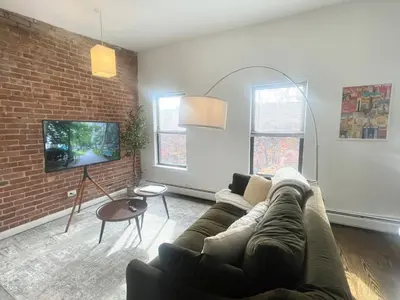 a living room with a couch and a brick wall at Perfect for Extended Stay 1B1B Apt 15 Mins to NYC in Jersey City