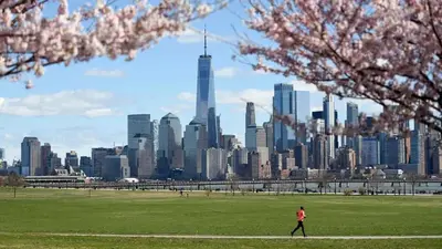 a person walking in a park with a view of a city at Perfect for Extended Stay 1B1B Apt 15 Mins to NYC in Jersey City