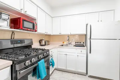 a kitchen with white cabinets and a refrigerator at Stunning 3 Bed Fully Furnished Apt in New York