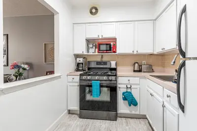 a kitchen with white cabinets and a stove top oven at Stunning 3 Bed Fully Furnished Apt in New York