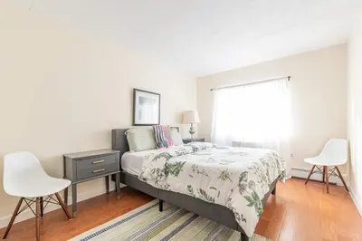 a bedroom with a bed and two white chairs at Stunning 3 Bed Fully Furnished Apt in New York