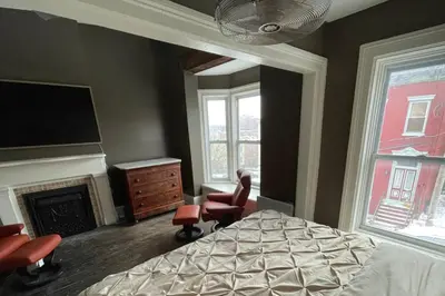 a bedroom with a bed and two chairs and a fireplace at Downtown 3BR duplex full kitchen parking off i-787 in Albany
