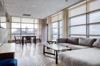a living room with a couch and tables and windows at Blueground East Harlem pool nr Central Park NYC-687 in New York
