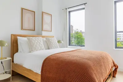 a white bedroom with a bed with a orange blanket at Blueground South Williamsburg washer nr Domino Park NYC-1866 in Brooklyn